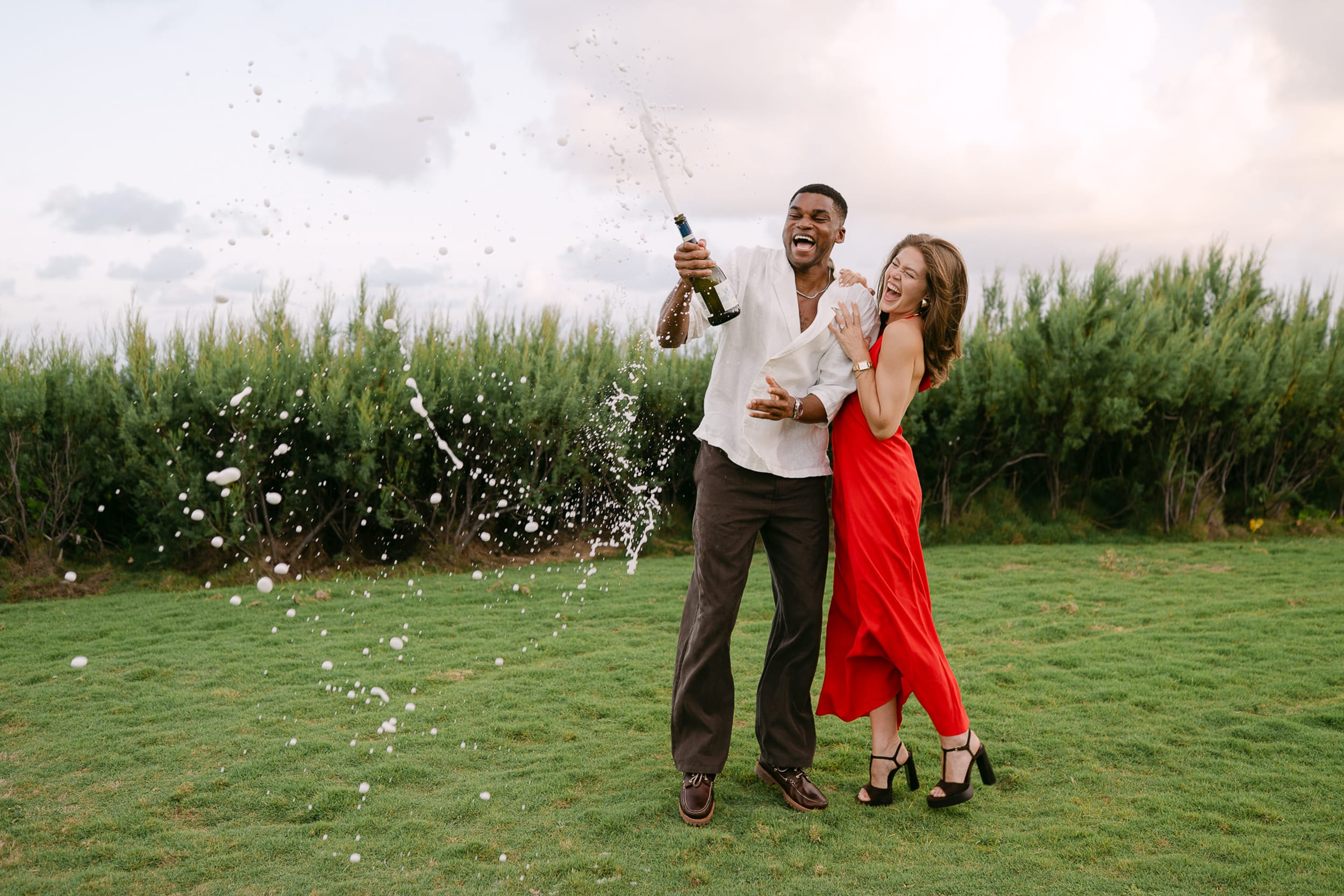 Recently engaged man and woman pop a bottle of Champagne after their proposal at The Crane Hotel in Barbados. Photo by Aniya Emtage