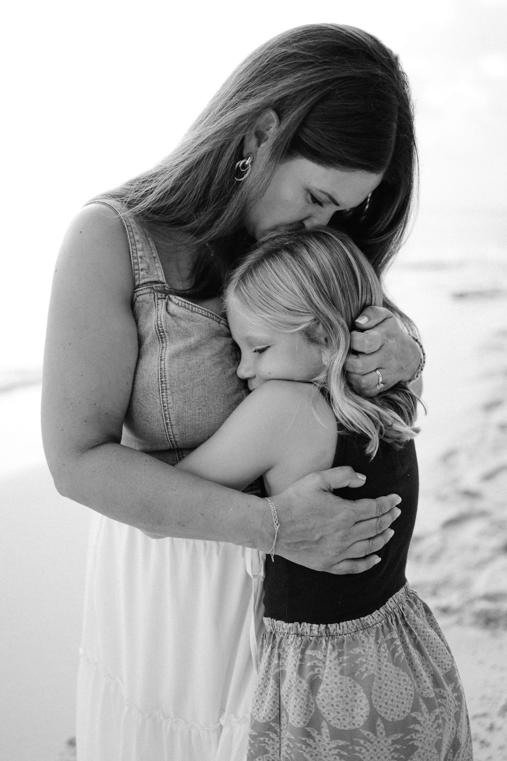 Mom and daughter hugging on the beach in Barbados during family photoshoot.