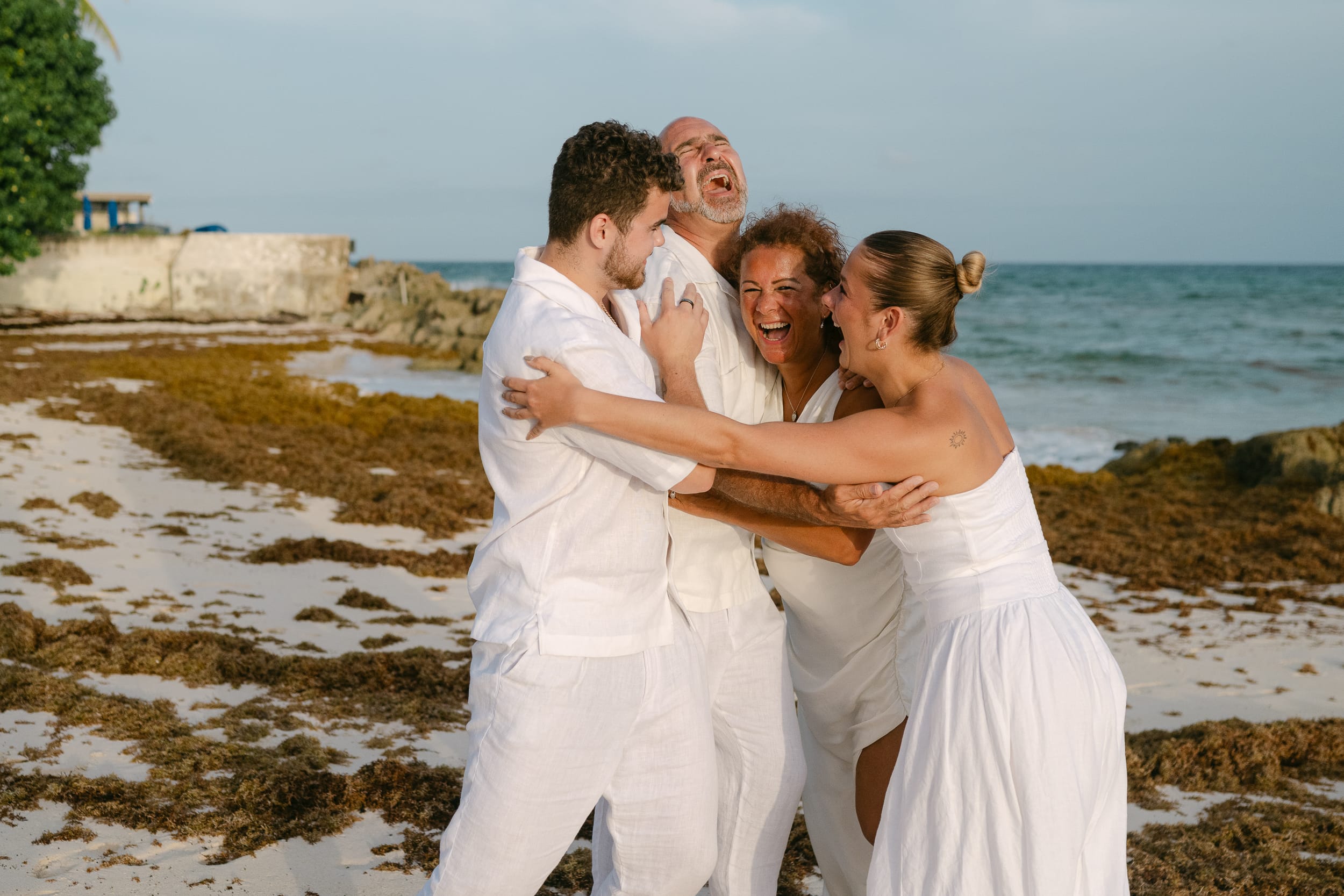 Family hugging and laughing on the beach in Barbados during a family photoshoot