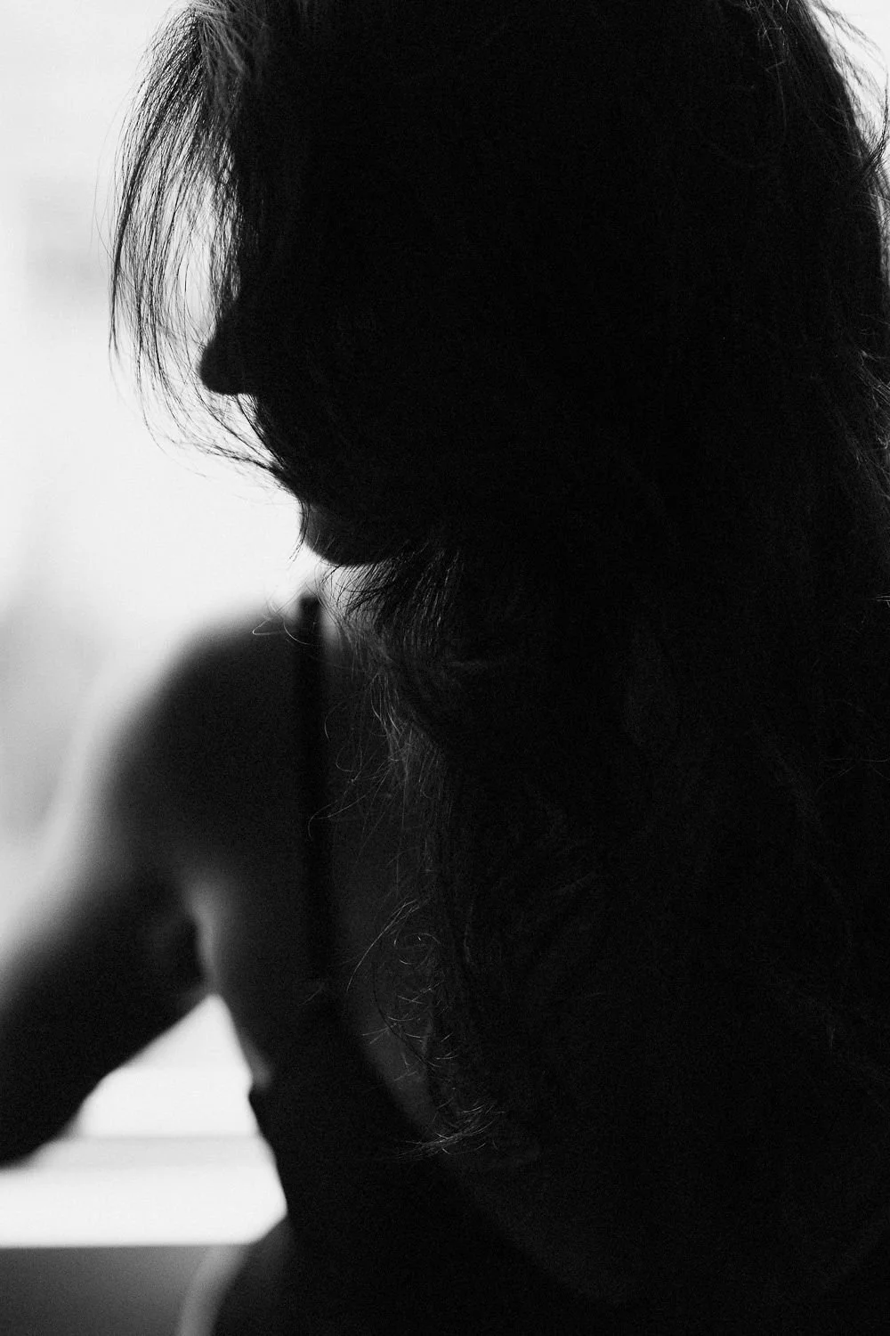 Black and white silhouette of a woman with long, wavy hair, with her face turned to the side.