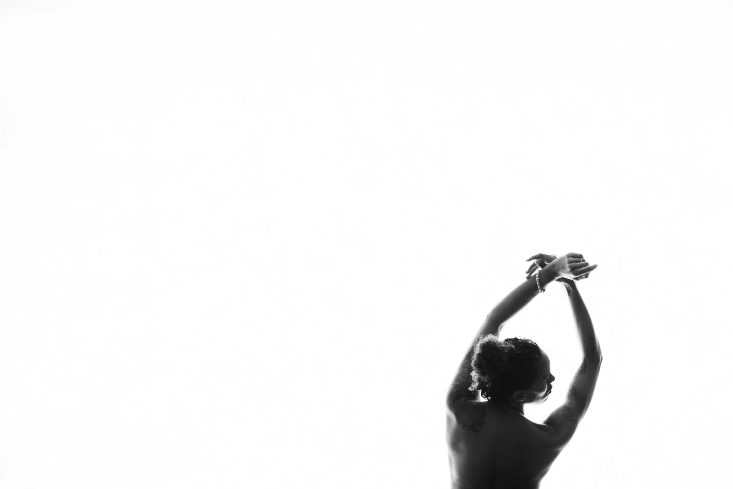 Black and white silhouette of a woman with arms raised above her head, against a white background.