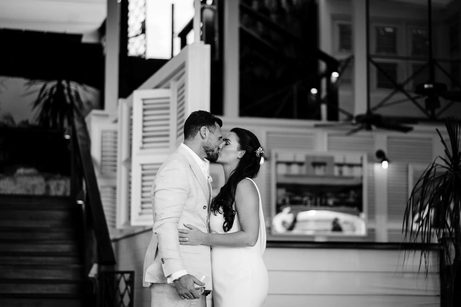 A black and white photo of a couple kissing, standing close together indoors, with a modern interior background.