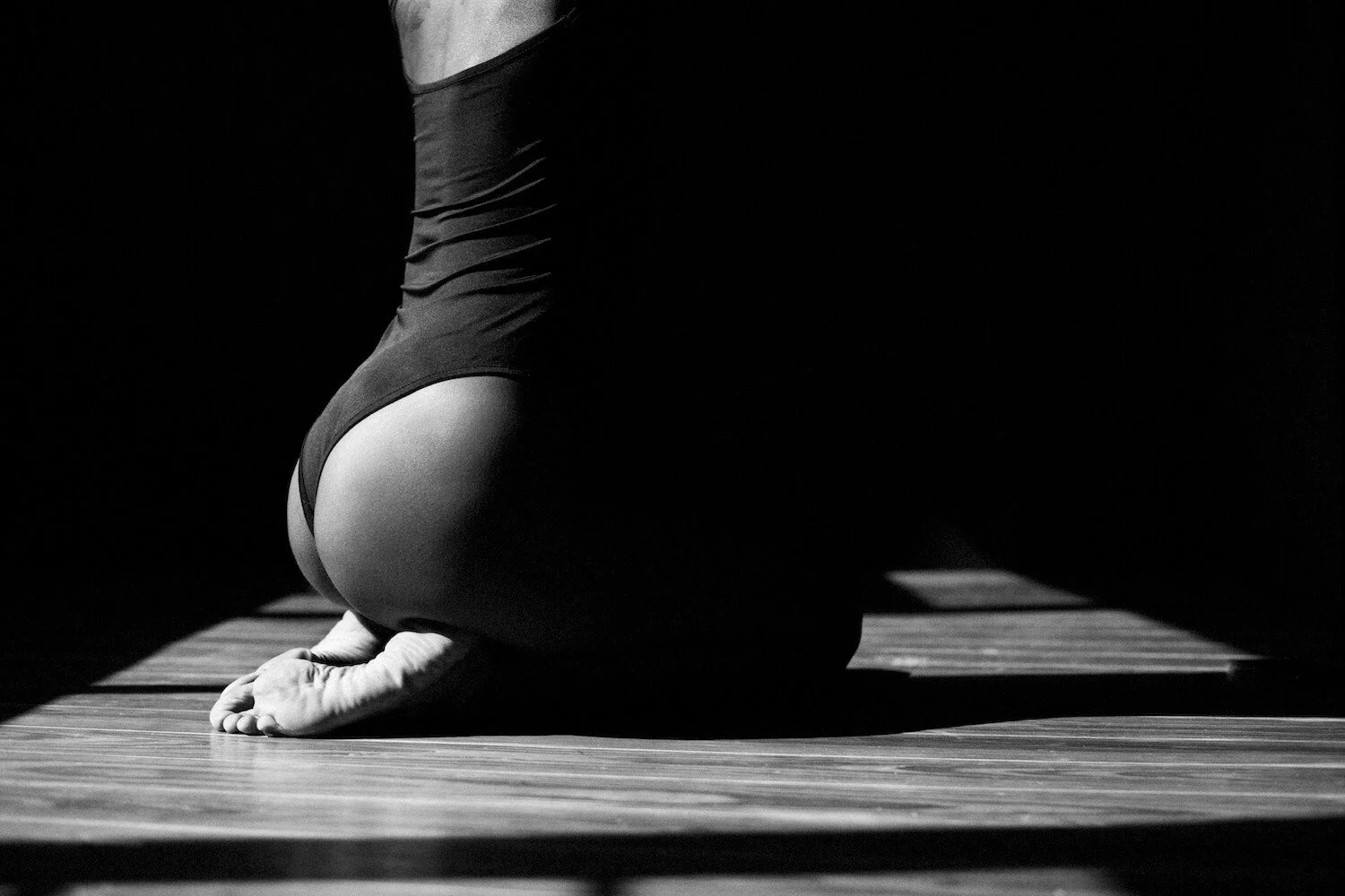 Close-up of a person doing a yoga pose on a wooden floor, black and white photo.