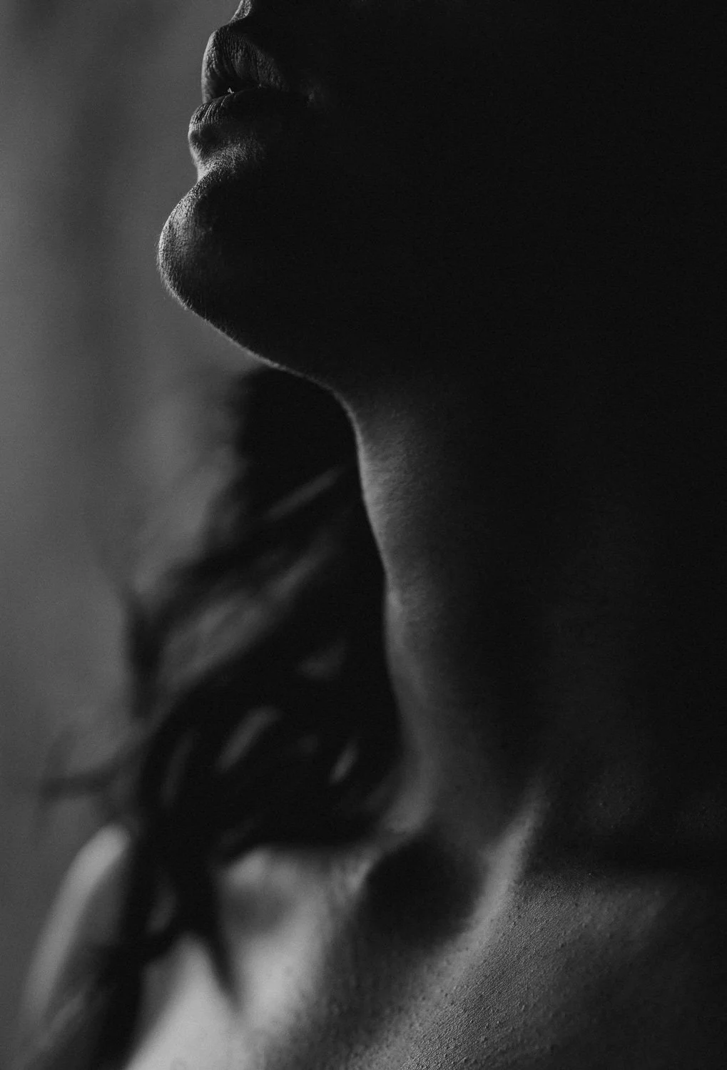Close-up silhouette of a person's face with finger on lips, in black and white.