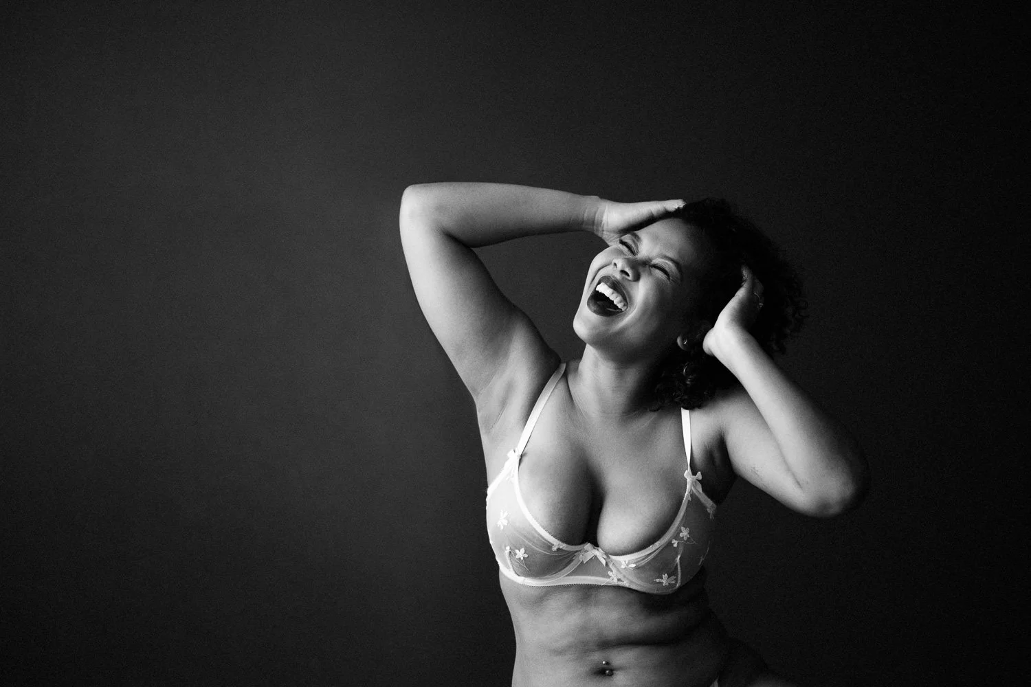 Woman laughing with her hands in her hair during a boudoir session in Barbados. Photo by Aniya Emtage