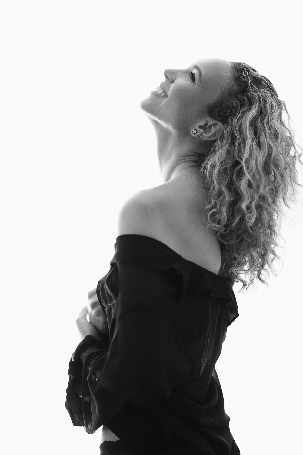 woman laughing in the air while holding rode during a boudoir session in Barbados. Photo by Aniya Emtage