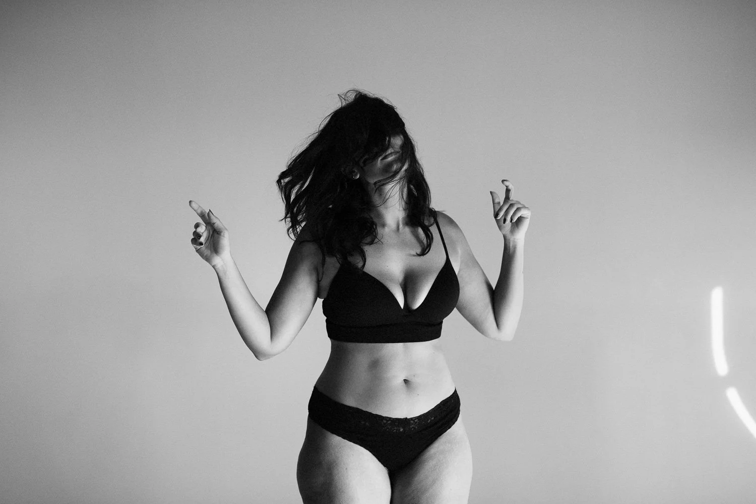 Black-and-white photo of a woman in underwear dancing with her hair covering her face.