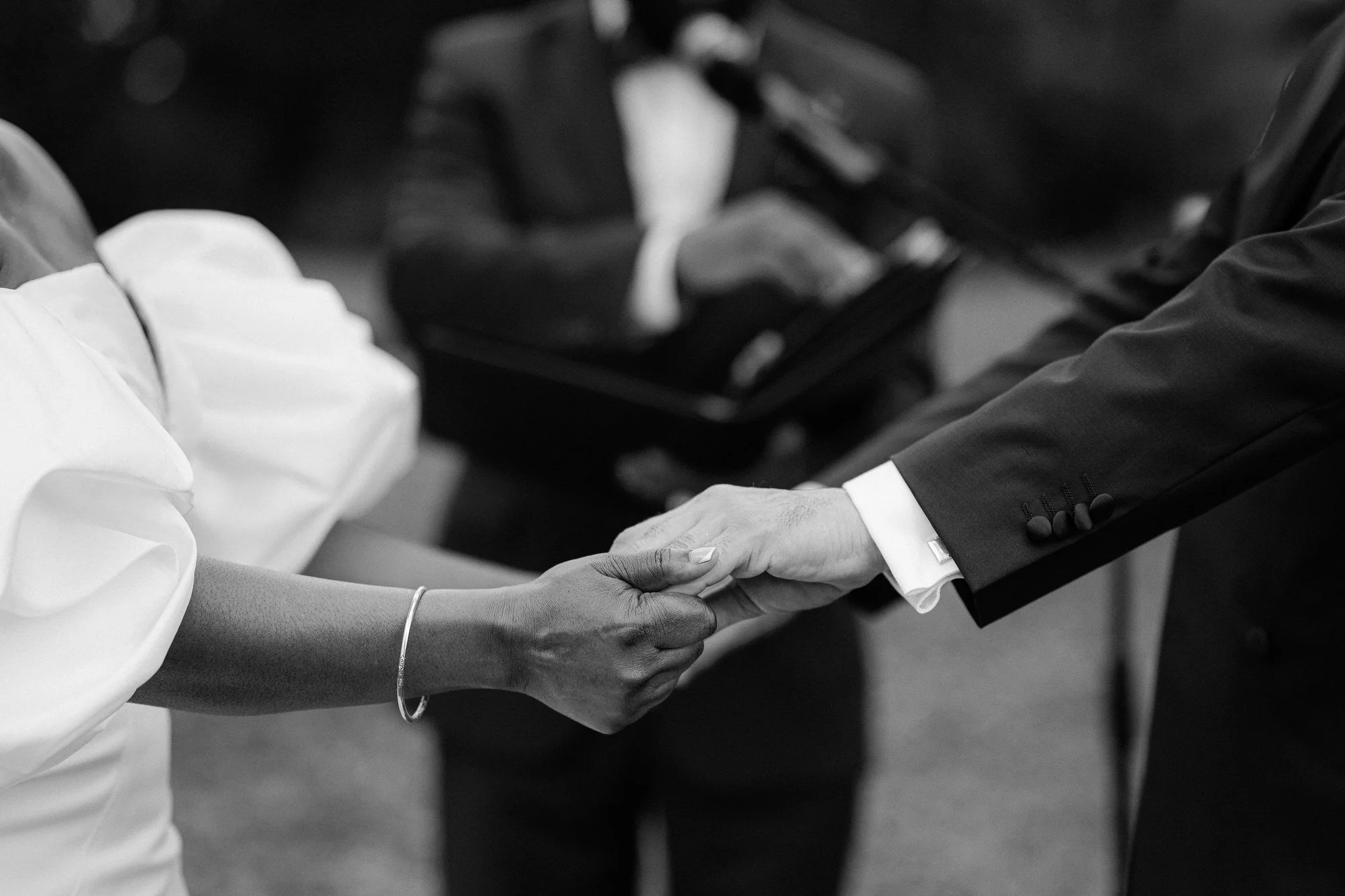 A Black woman in white clothing shaking hands with a man in a suit at a formal event.
