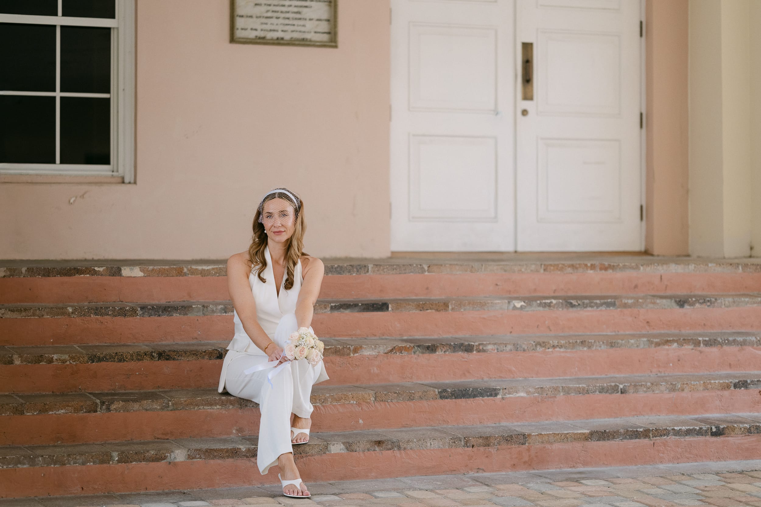 Bride sitting on the stairs after her barbados courthouse wedding
