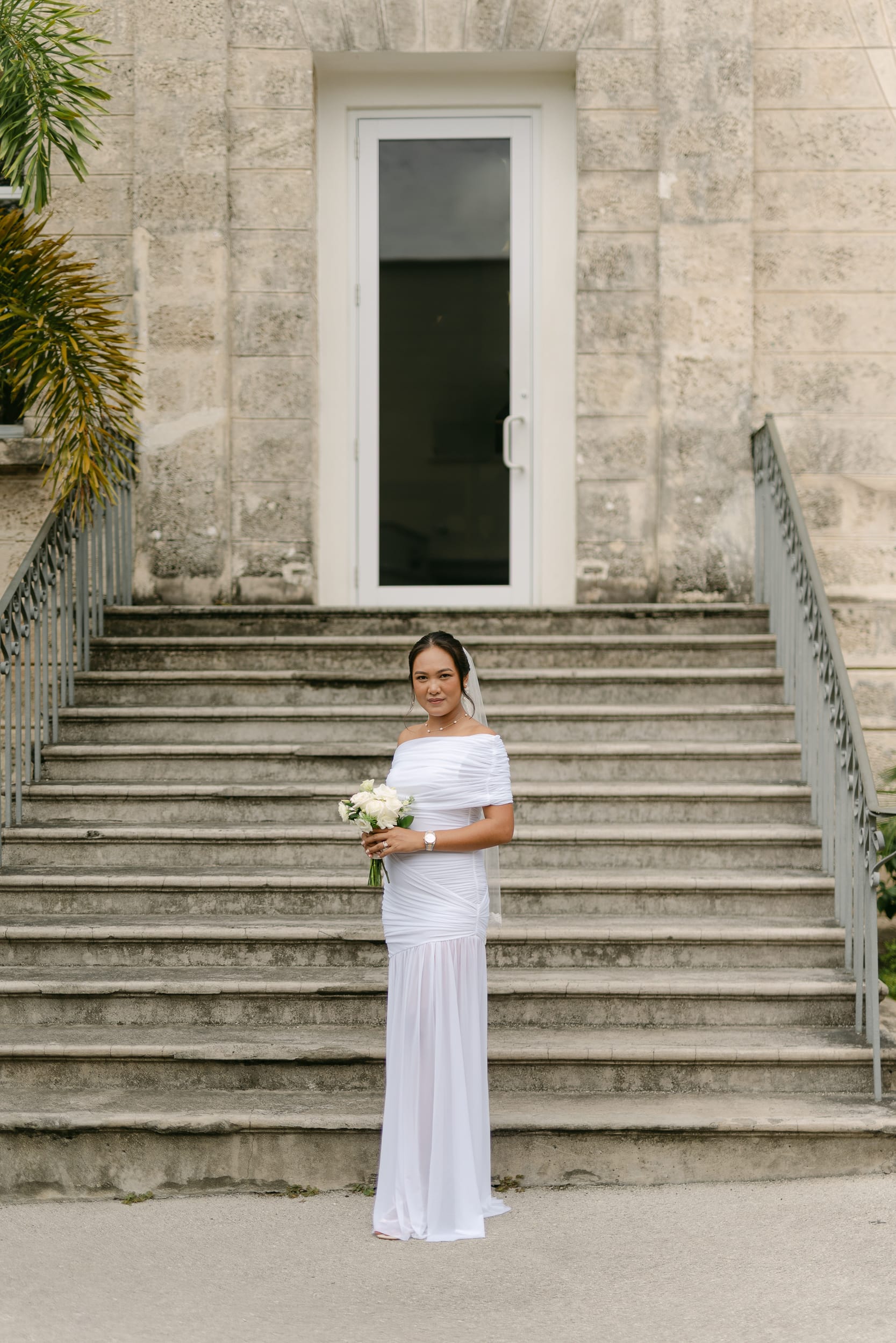 bride stands at the bottom of the stairs after her Barbados courthouse wedding
