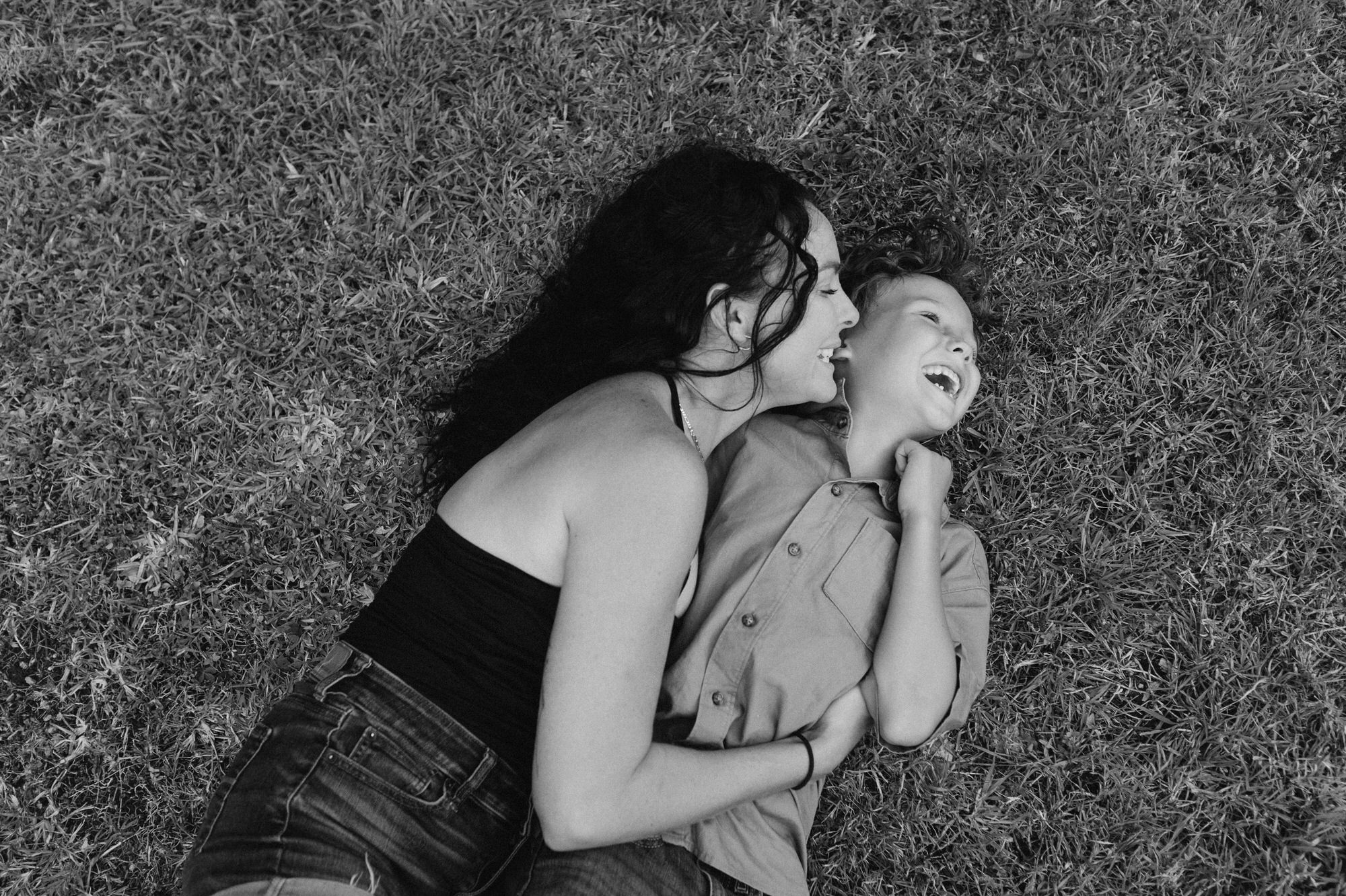 mom laughing with son on the grass