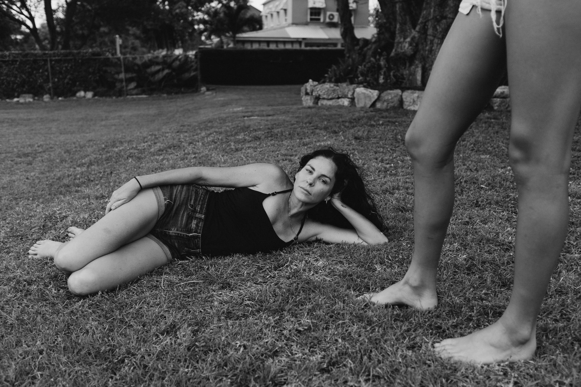 Mom lying down on the grass with her family standing around her