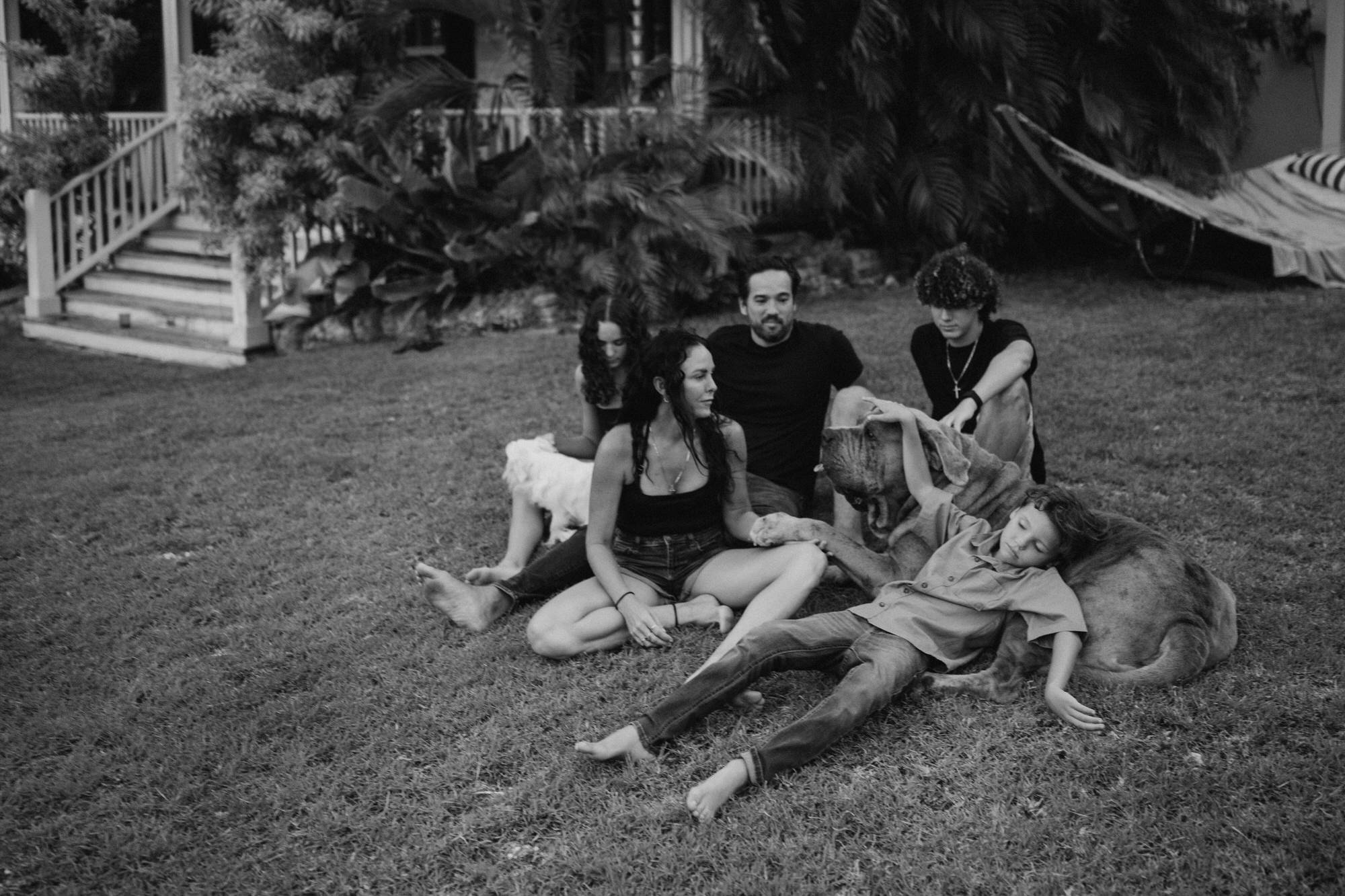 family altogether lying on the grass with son lying on the dog