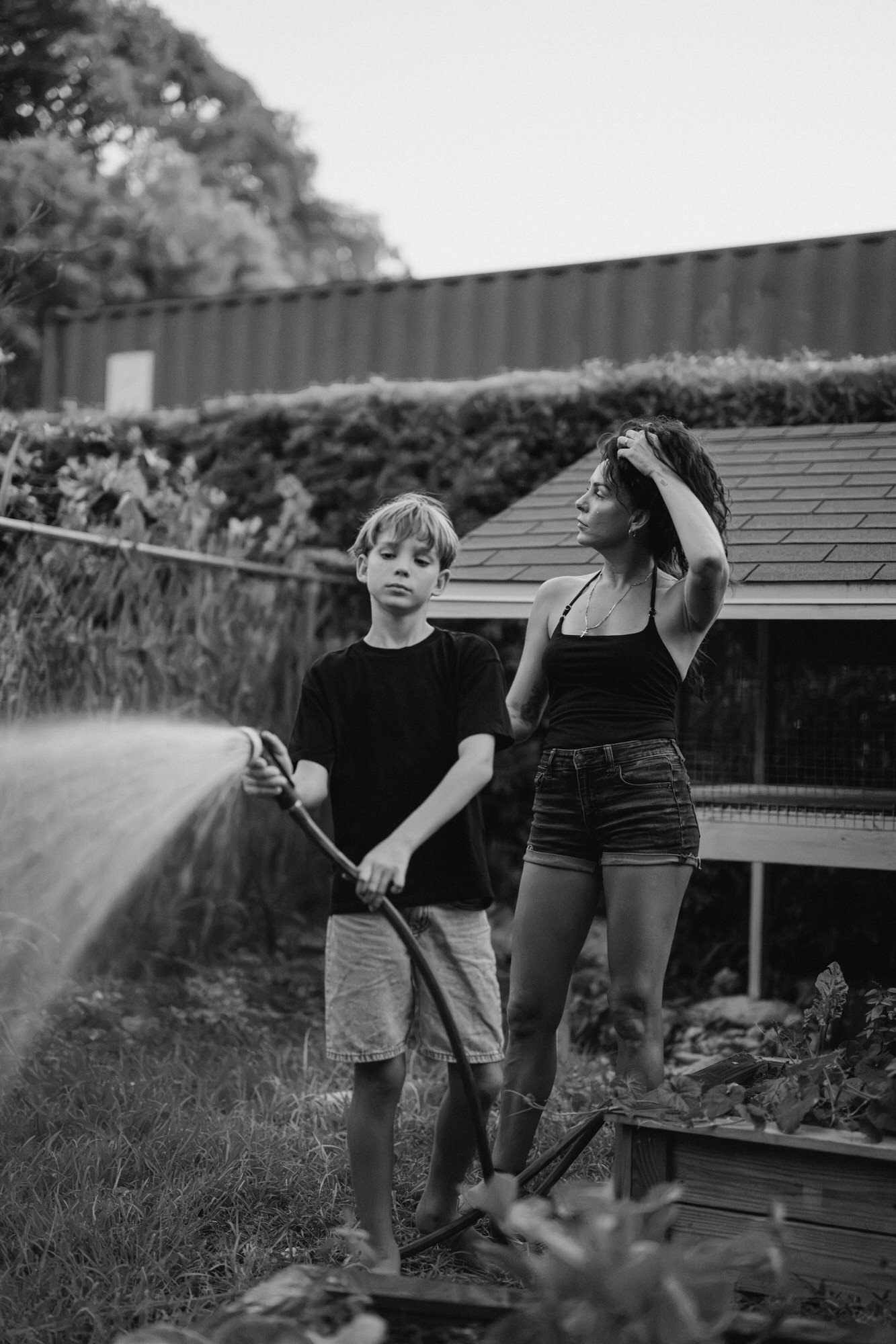 mom is with her son as he waters the garden